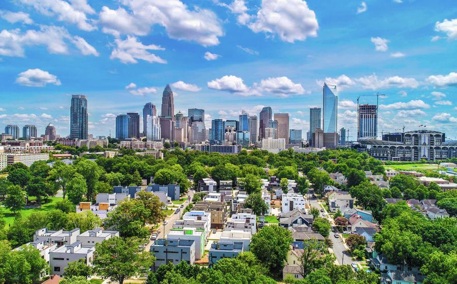 Charlotte, North Carolina aerial view of the city with residential apartment buildings in the front surrounded by Lush trees and skyscrapers off in the distance