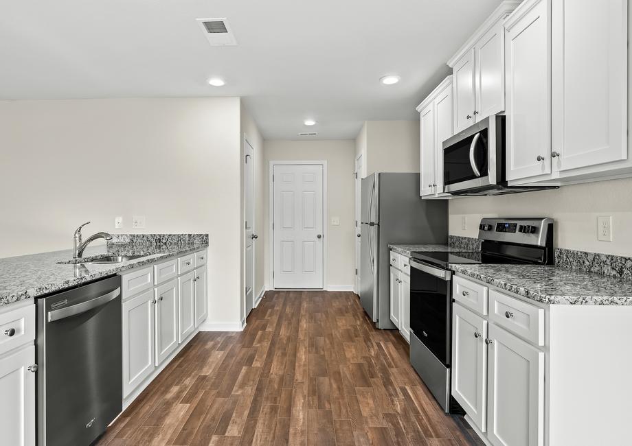 Kitchen complete with stainless steel appliances, granite countertops, cabinets with hardware and luxury vinyl plank flooring.