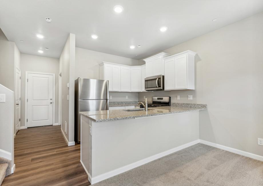 The kitchen has the stainless steel appliances and plank flooring.