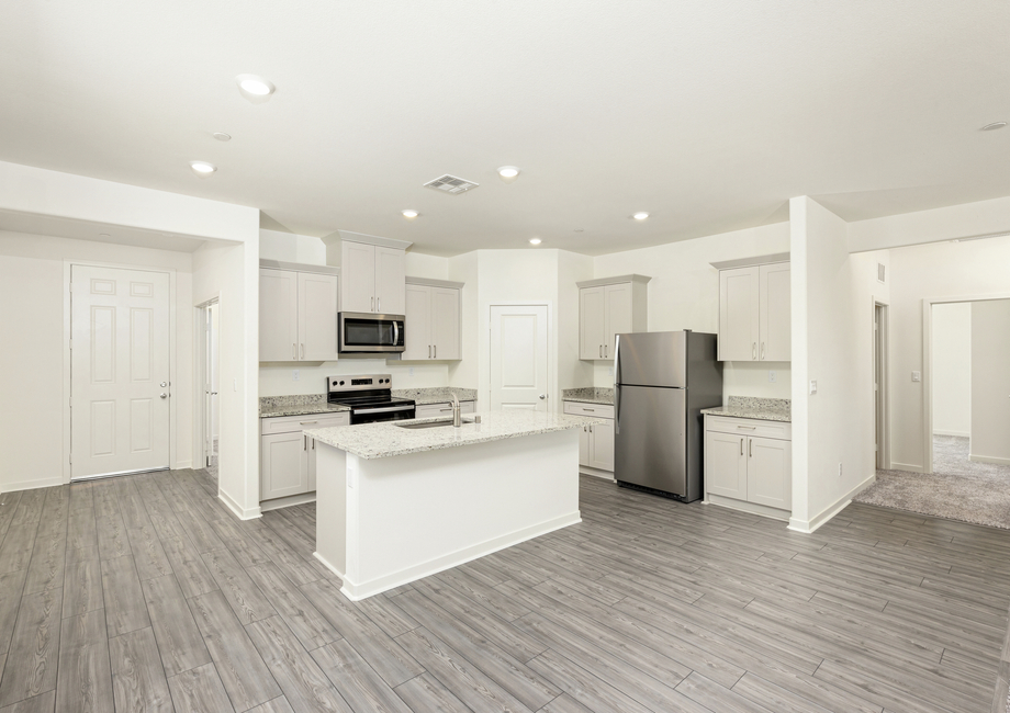 The kitchen has stainless steel appliances and plank flooring.