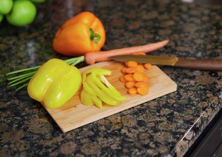 Trace kitchen with dark brown granite, chopping board, and sliced veggies