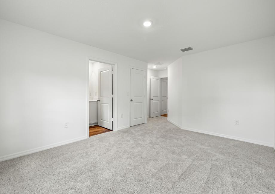 A large master bedroom with white walls and light carpet.