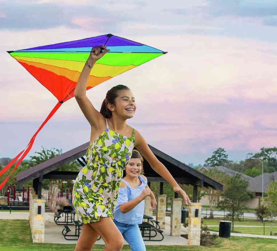 Young children running and playing with a kite outside. 