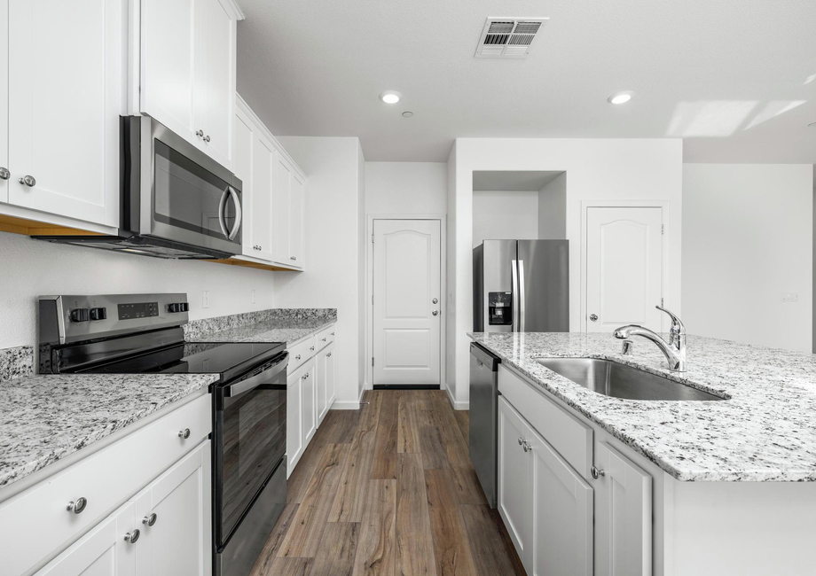 The kitchen has stainless steel appliances and plank flooring.