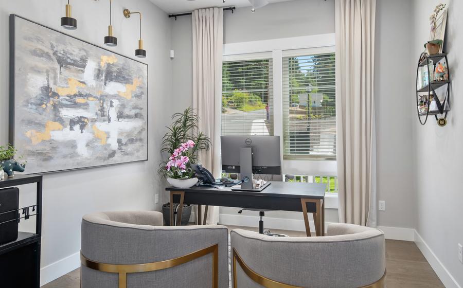 Home office with a large window, wood flooring and modern furniture.