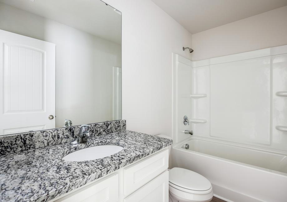 Secondary bathroom with white cabinets and a granite countertop.