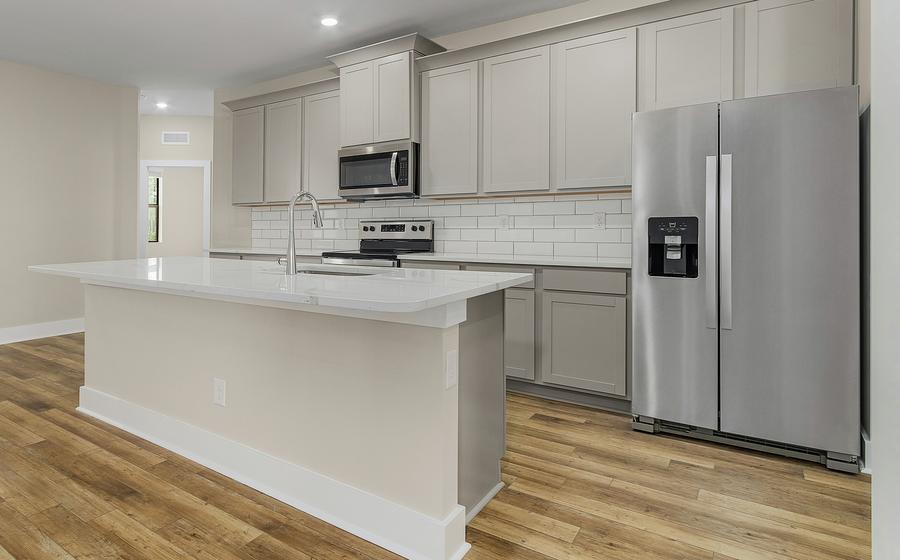 Spacious kitchen with gray cabinets, large island and white subway tile backsplash.