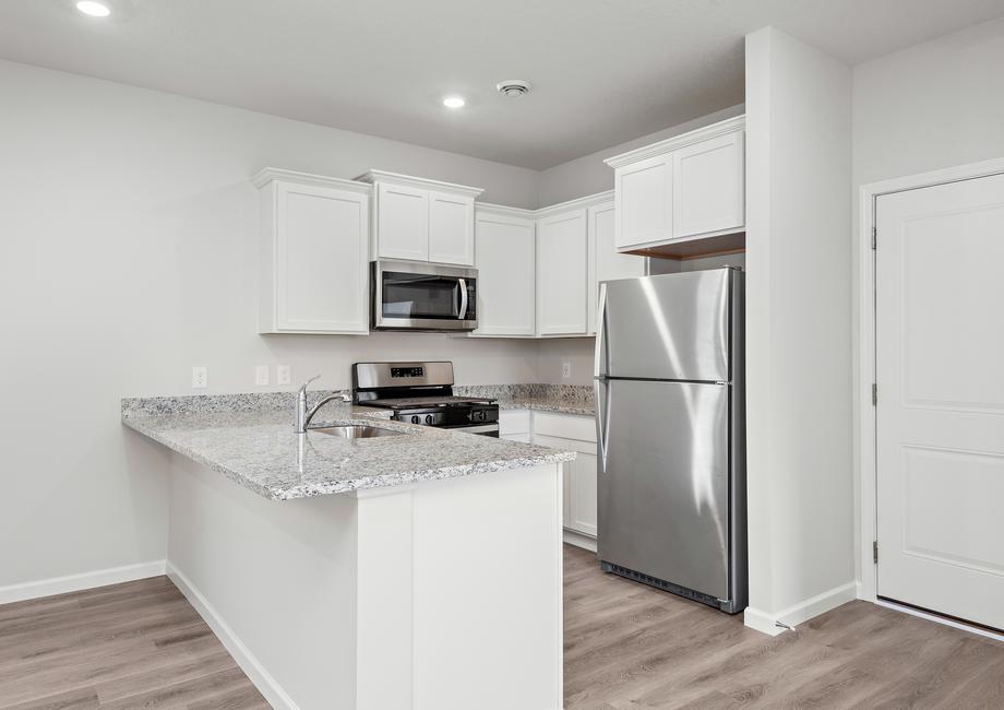 The kitchen has stainless steel appliances and plank flooring.