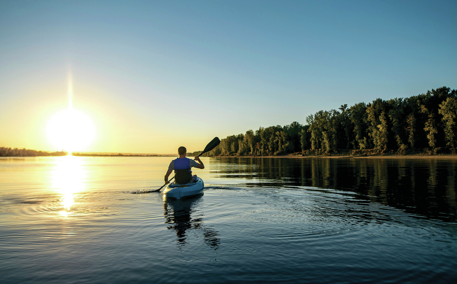 Man in kayak on river at sunset.