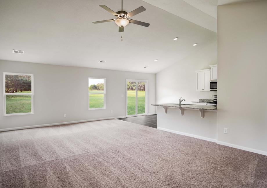 Open concept floor plan with a large living room featuring a ceiling fan.