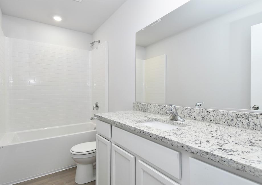 The secondary bathroom has a large vanity and tub shower combo.