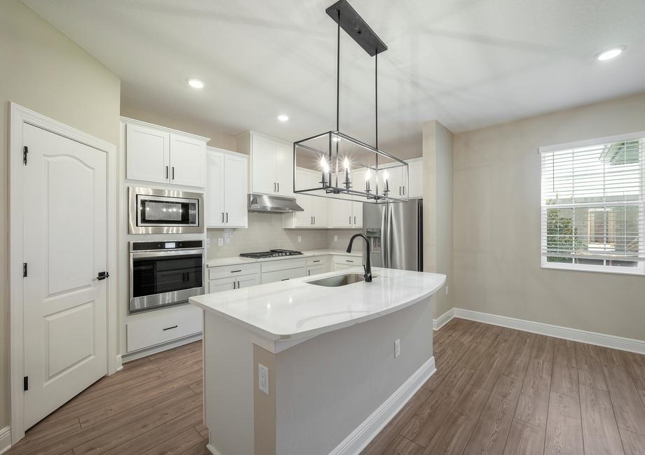 A white kitchen with a big middle island and stainless steel appliances.