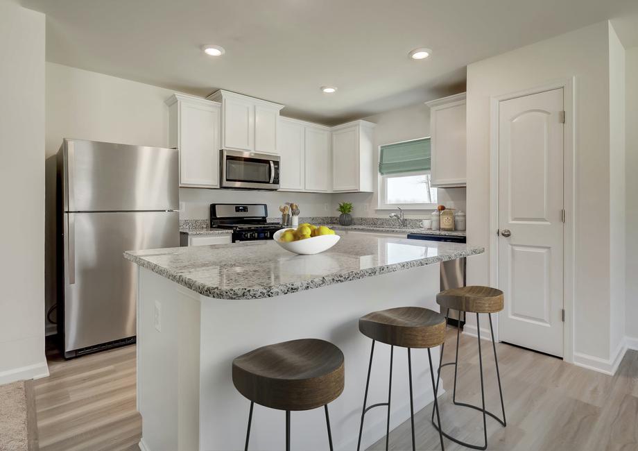 Staged kitchen with white cabinets, stainless appliances, three barstools, gray granite counters and light blue window shade.