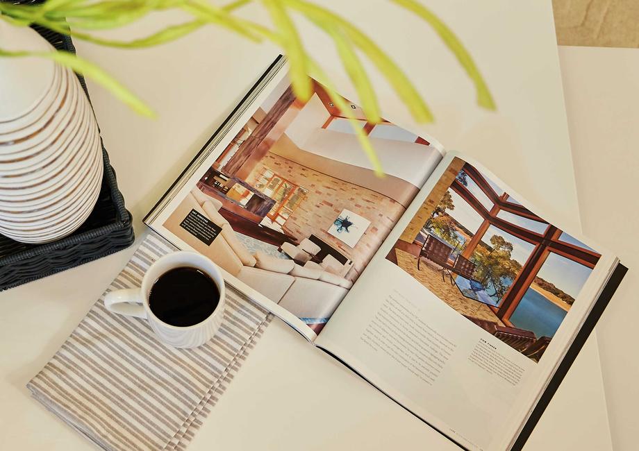 Staged image of coffee table with open book, plant vase and cup of coffee.