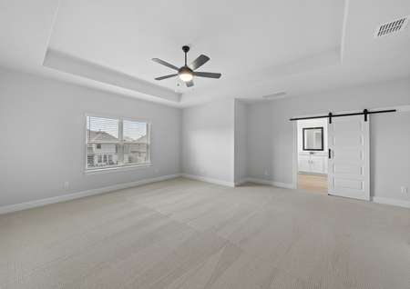 Spacious master bedroom with large windows, a ceiling fan, and wood flooring. 