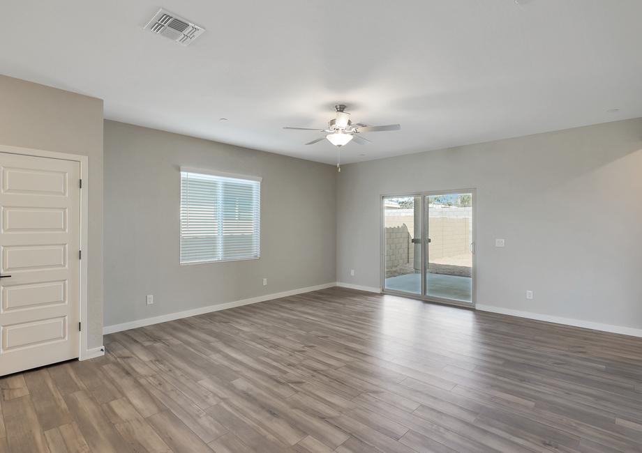 Spacious living room with wood-style flooring, a ceiling fan, and doors leading outside.