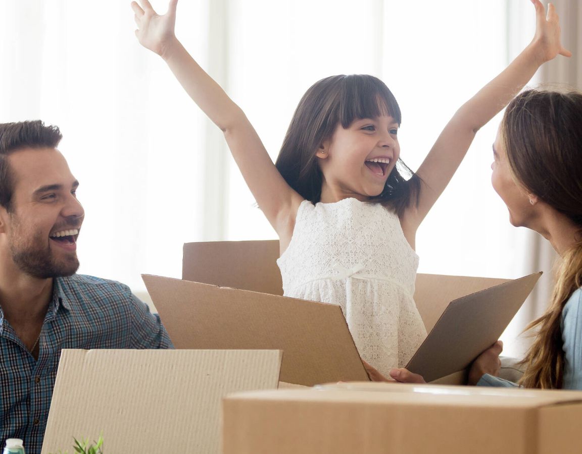 Family unpacking boxes, happy girl with arms in air