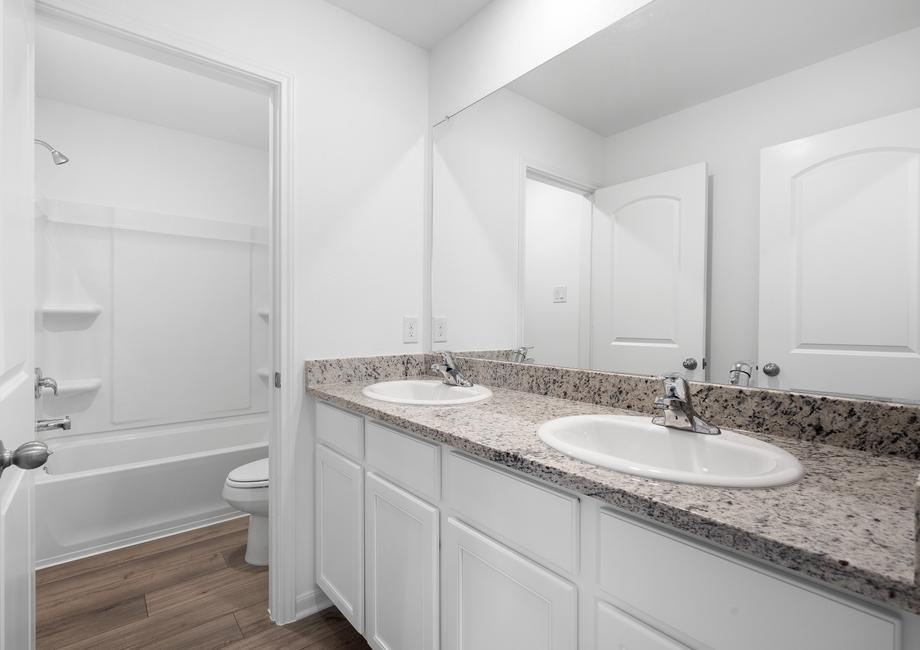 Secondary bathroom with granite countertops and white cabinets.