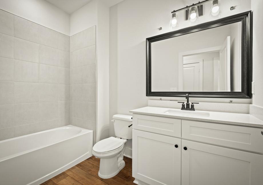 Secondary bathrooms have framed mirrors and large vanities.