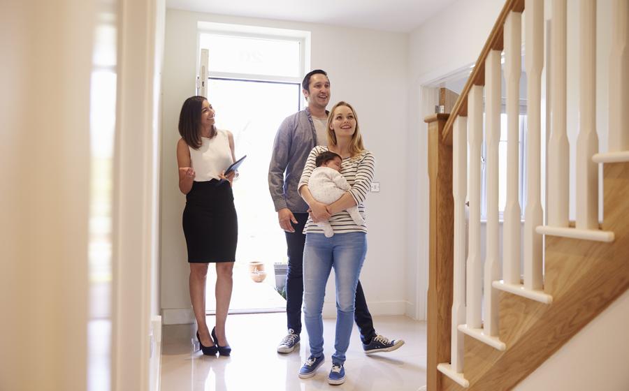 A couple with a baby tour a home with their sales consultant.