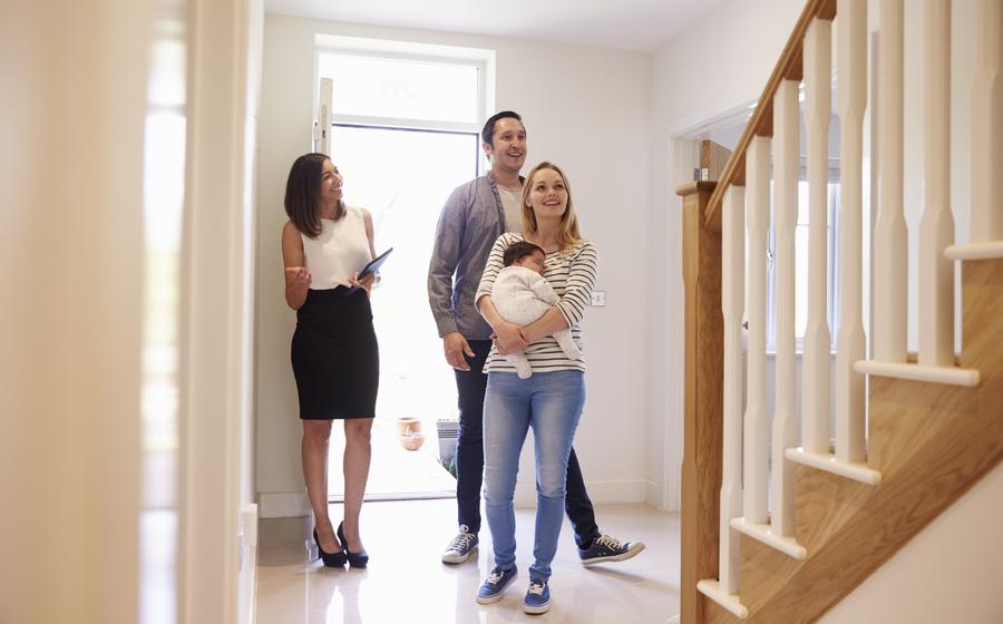 A couple with a baby tour a home with their sales consultant.