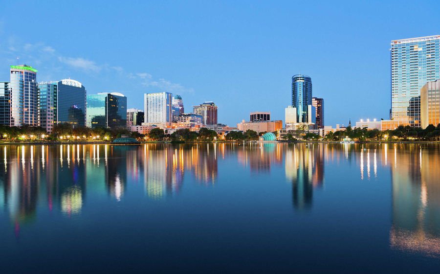 Orlando, Florida skyline at sunrise from Lake Eola showing calm waters and large office buildings reflecting in the water