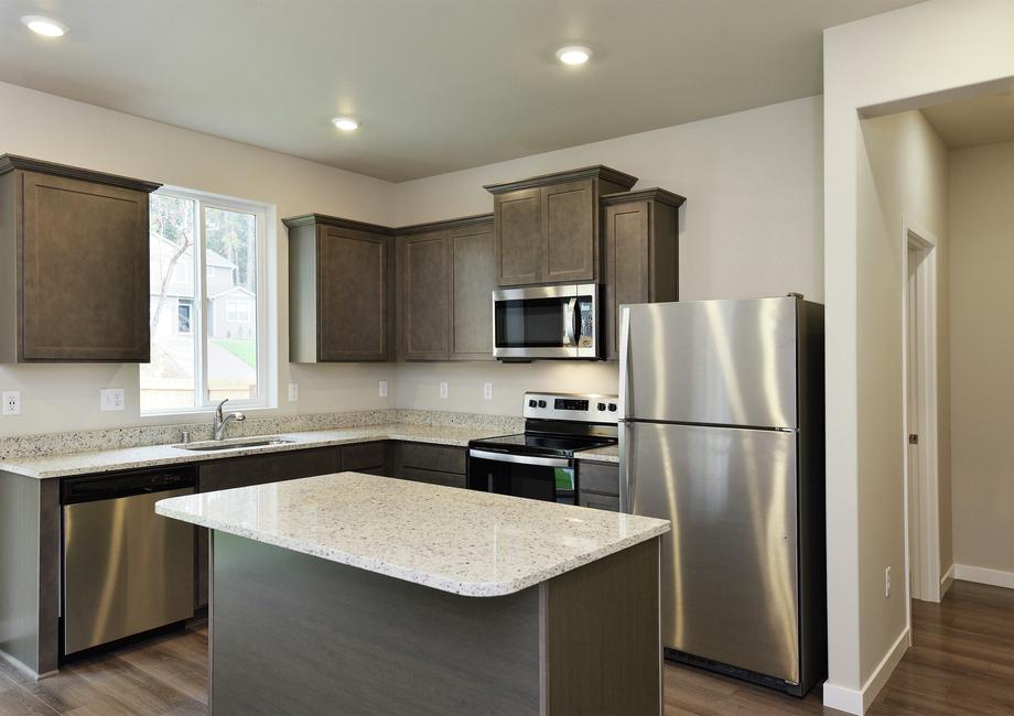 The kitchen has stainless steel appliances and plank flooring.