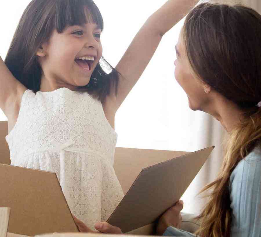 Stock image of family unpacking boxes, little girl excited with hands in the air.