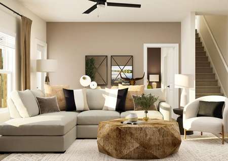 Rendering of the living room in the
  Twinberry floor plan. It is furnished with a sectional couch, accent chair,
  large coffee table and a rug. The entrance to the master bedroom is visible
  behind the couch.