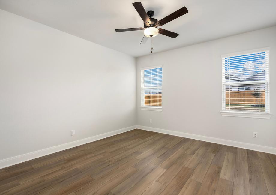 Spacious master bedroom with a ceiling fan and wood-style flooring.