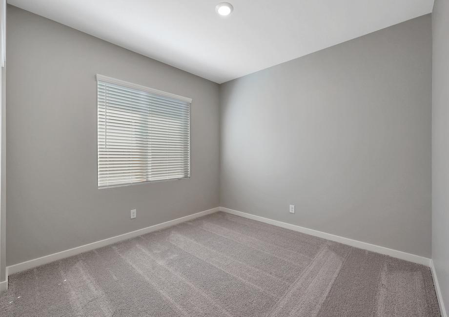 Secondary bedroom with a large window, tan carpet, and recessed lighting.