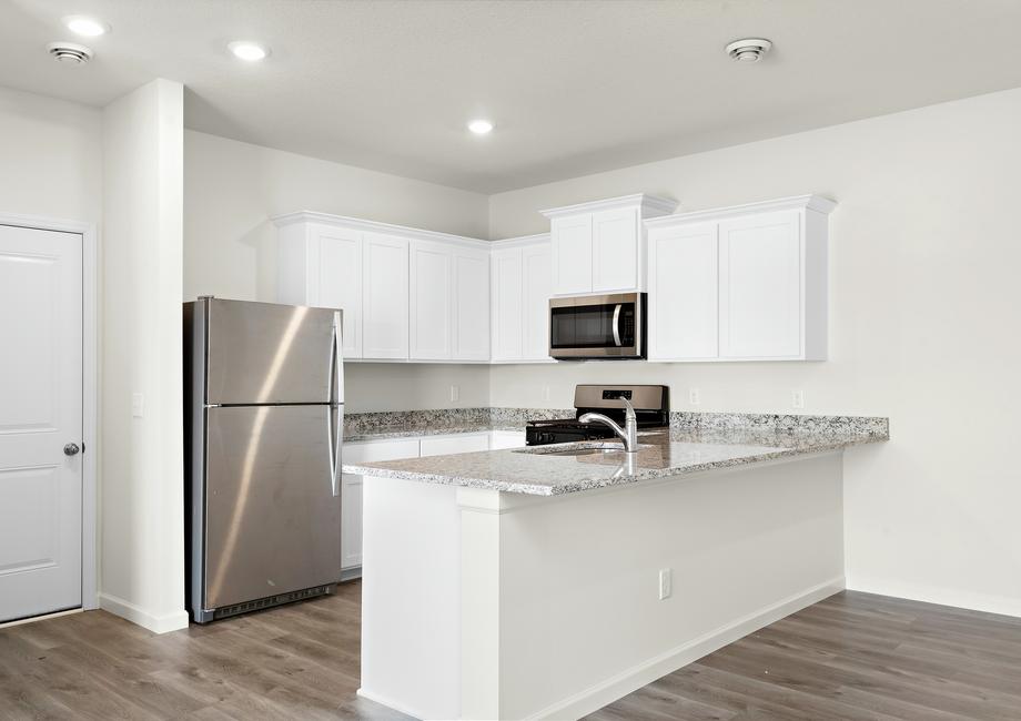 The kitchen has stainless steel appliances and plank flooring.