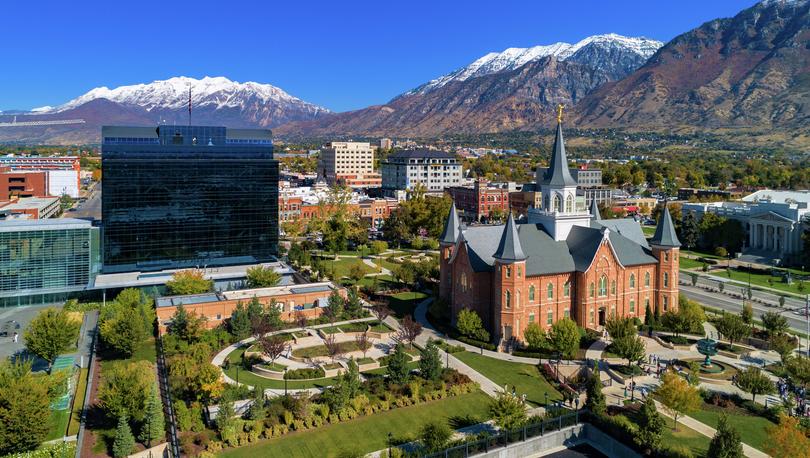 Aerial of downtown Provo, Utah showing the Provo City Center Temple and One Nu Skin Plaza, with the snow capped Wasatch Mountain Range in the background.