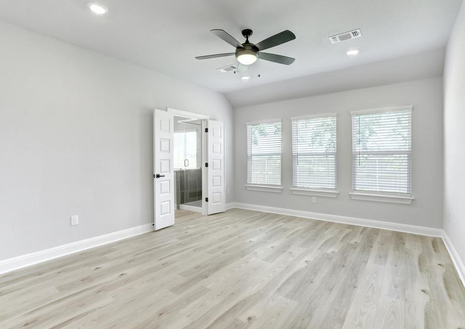 Spacious master bedroom with large windows, a ceiling fan, and wood flooring.