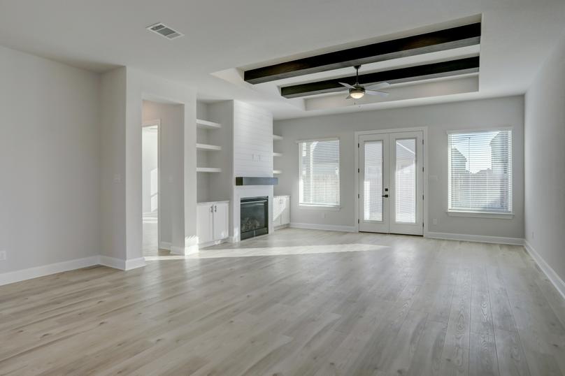 Expansive living room with a fireplace, floating shelves, and large windows.