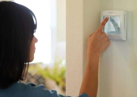 Trace homeowner adjusting programmable thermostat