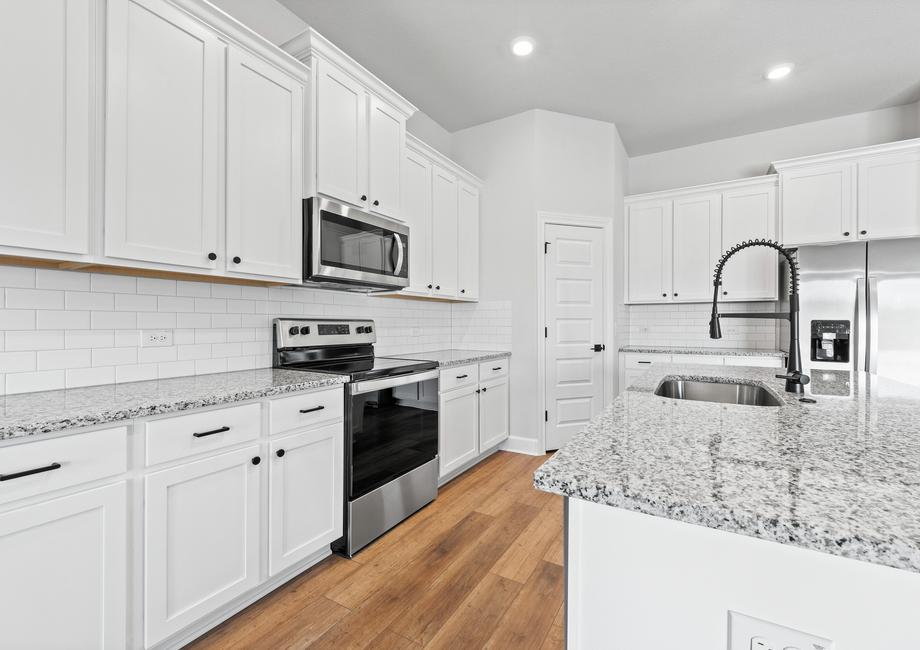 Take a closer look at this open concept kitchen, featuring white cabinetry, marble countertops, upgraded hardware, and stunning stainless steel Whirlpool appliances.