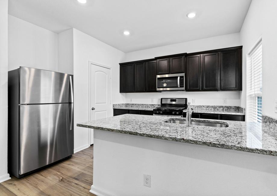 Designer kitchen with granite countertops, stainless steel appliances, and wood-style flooring.