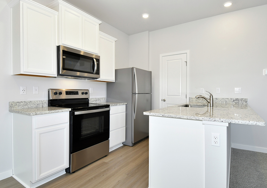 The kitchen has stainless steel appliances and plank flooring.