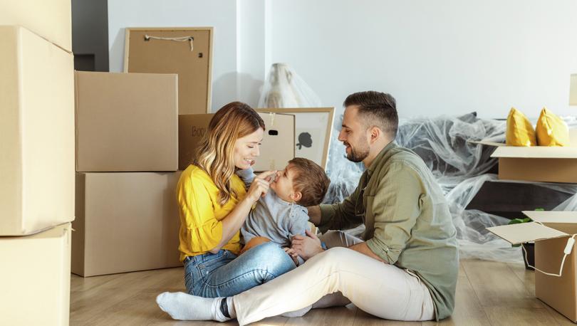 Couple sitting on the floor of their new home with their son between them.