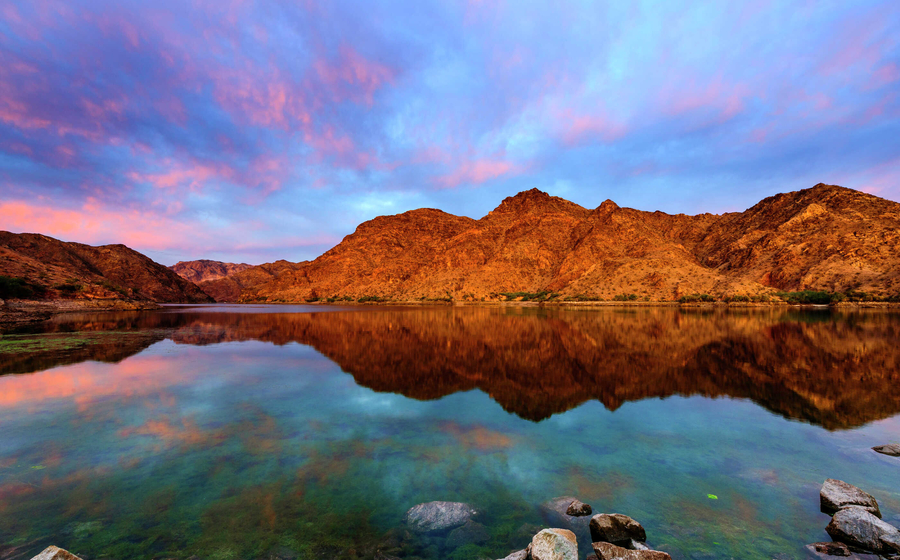Nevada Colorado River sunrise with the sky reflecting off of the still water and rocky mountains in the background