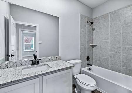 The bathroom of the Michigan has beautiful granite countertops and a bathtub-shower combination.