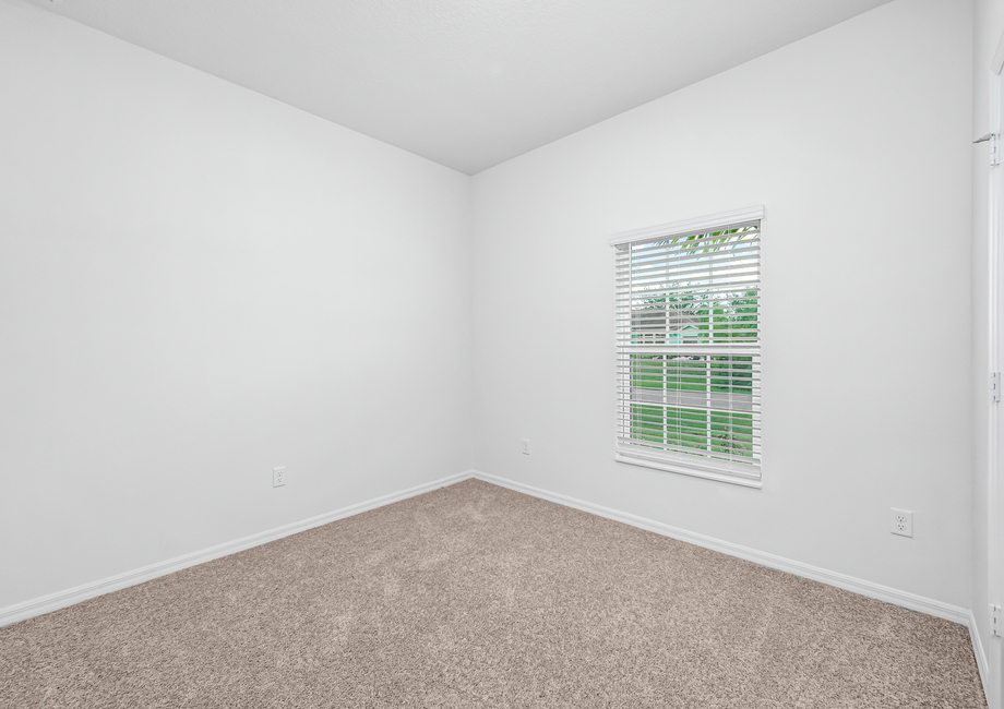 A secondary bedroom with lush carpet