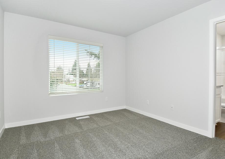The master bedroom has carpet and a large window.