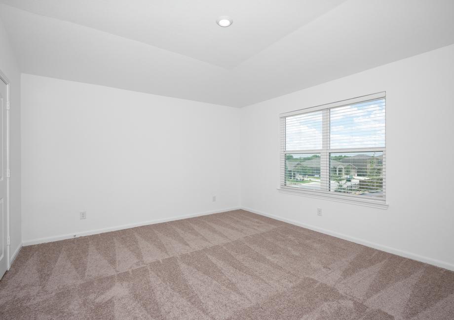Master bedroom with a vaulted ceiling, recessed lighting, and large windows.