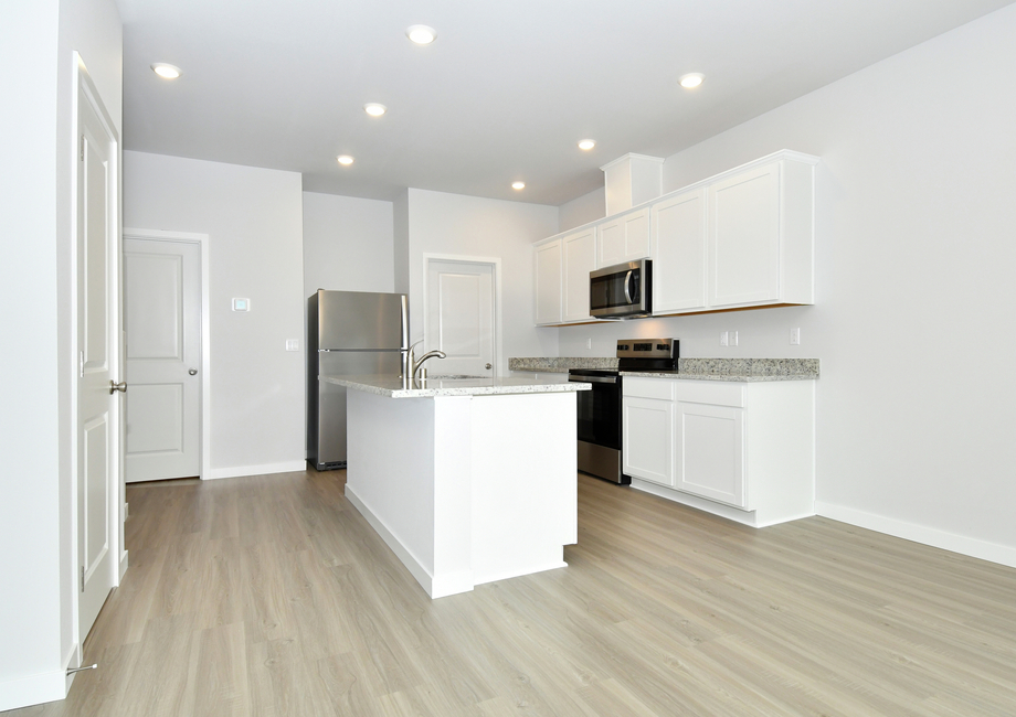 The kitchen has stainless steel appliances and plank flooring.