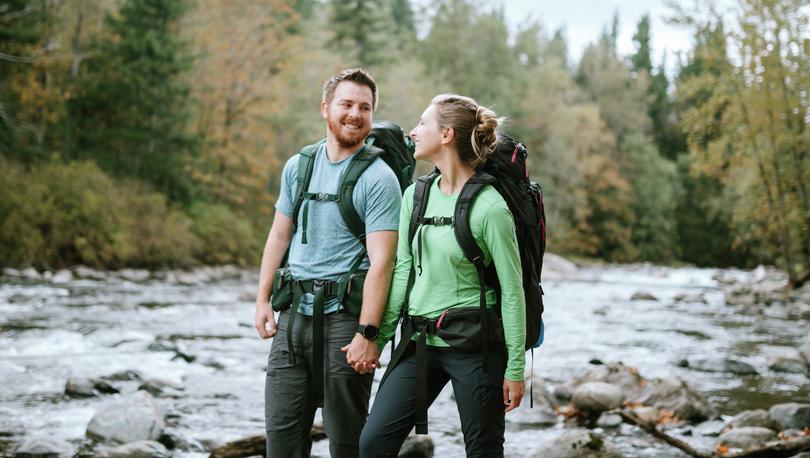 Photo of a young couple backpacking along a river in Washington state in fall.