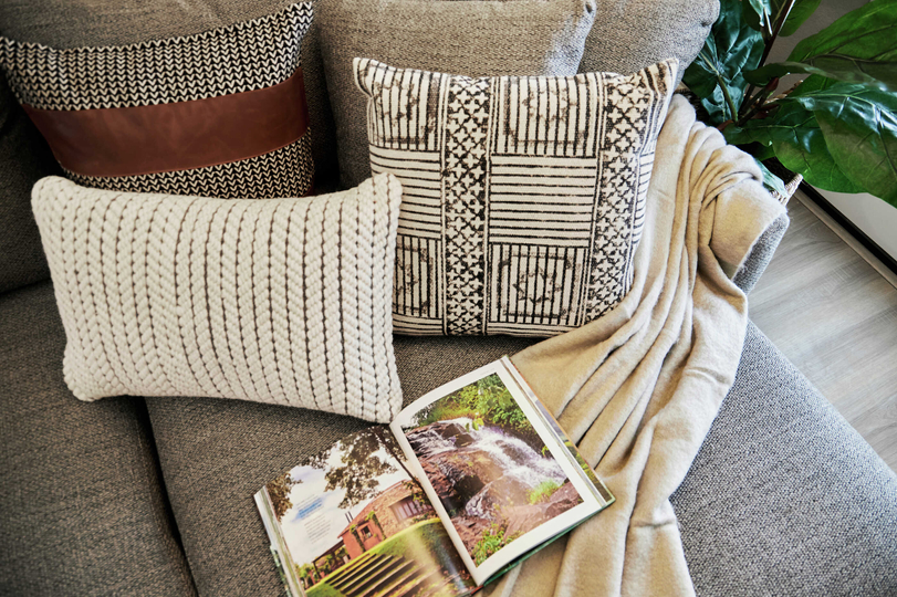 Staged couch with open book, pillows and blanket.