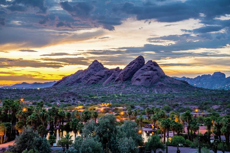 Phoenix, Arizona Papago Park buttes with palm trees and houses in the forefront and mountains in the background