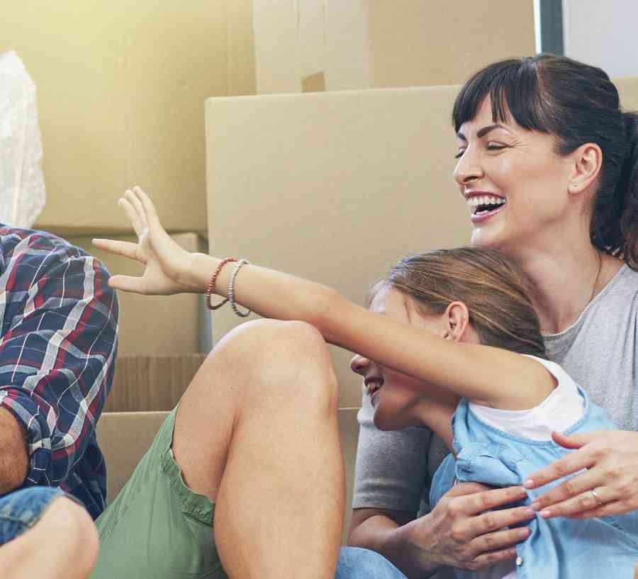 Family sitting on the floor surrounded by moving boxes.